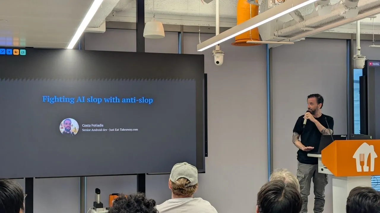 Costa on stage with a microphone next to a slide titled Fighting AI slop with anti-slop